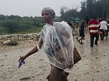 A woman protects herself from the rain with a piece of plastic prior the arrival of Hurricane Matthew, in Tabarre, Haiti, Monday, Oct. 3, 2016. The center of Hurricane Matthew is expected to pass near or over southwestern Haiti on Tuesday, but the area is already experiencing rain from the outer bands of the storm. (AP Photo/Dieu Nalio Chery)