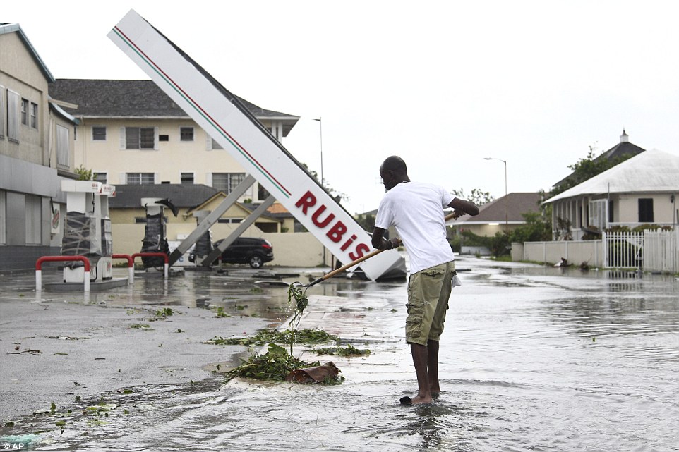 Marco Beckford rakes up debris from a storm drain as he begins cleanup near a damaged gas station in the aftermath of Hurricane Matthew in Nassau, Bahamas