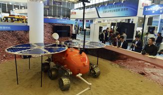 FILE - In thi Nov. 4, 2014, file photo, visitors to the 16th China International Industry Fair (CIIF) look at a prototype of what a Chinese Mars rover would look like in Shanghai, China. Head of the China National Space Administration Xu Dazhe said Friday, April 22, 2016 at a rare news conference that plans are being drawn up for the project that was formally announced in January and that it has the government&#39;s full support. (Chinatopix Via AP, File) CHINA OUT