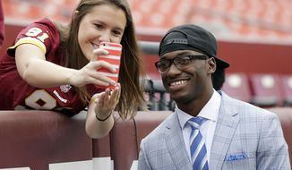 Injured Cleveland Browns quarterback Robert Griffin III takes a selfie with a Washington Redskins fan before an NFL football game Sunday, Oct. 2, 2016, in Landover, Md. (AP Photo/Mark Tenally)