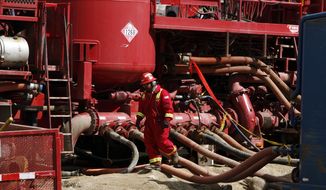 A worker steps through the maze of hoses being used at a remote fracking site in Rulison, Colorado. (Associated Press/File)
