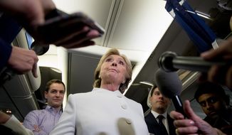 Democratic presidential candidate Hillary Clinton, center, accompanied by Campaign Manager Robby Mook, left, and traveling press secretary Nick Merrill, right, takes a question from a member of the media aboard her campaign plane at McCarran International Airport in Las Vegas, Wednesday, Oct. 19, 2016, following the third presidential debate. (AP Photo/Andrew Harnik)