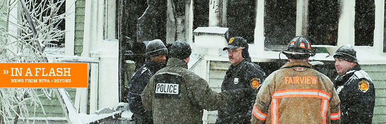 Firefighters and police stand outside a burnt house in the snow