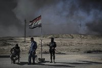 Guards stand at a checkpoint near burning oil fields in Qayara, south of Mosul, Iraq, Tuesday, Nov. 22, 2016. (AP Photo/Felipe Dana)