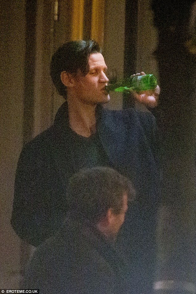 Thirsty work: He stood and sipped from a bottle of beer as the group chatted away