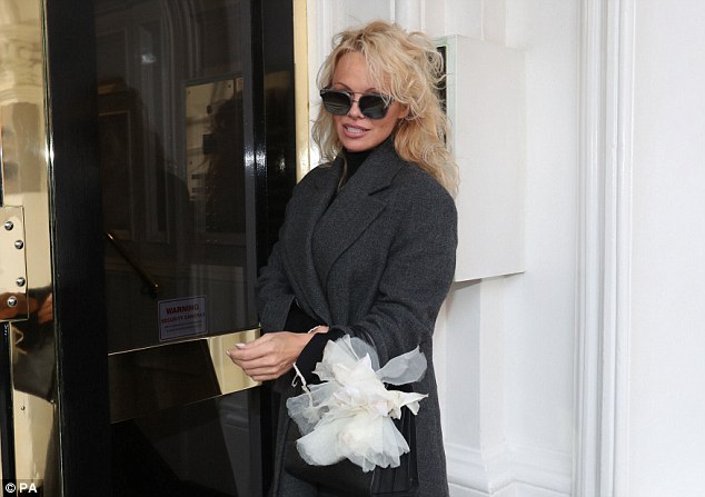 A few hours earlier: The former Baywatch star was pictured outside the Ecuadorian embassy in London, where her rumoured beau Julian Assange is living