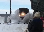 Here it comes: An Amtrak train is seen driving into snow, sending it flying on Wednesday 