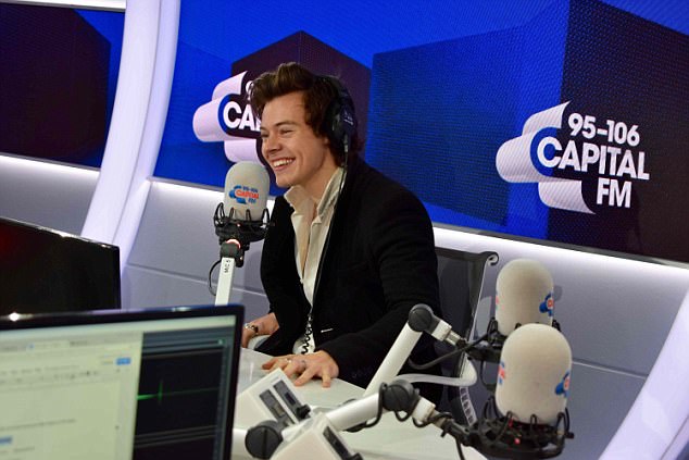 Cheeky chappy: Harry Styles joked that the tight harness used for the daring stunt 'helped with the high notes' as he chatted to Roman Kemp on the Capital London Breakfast Show on Friday