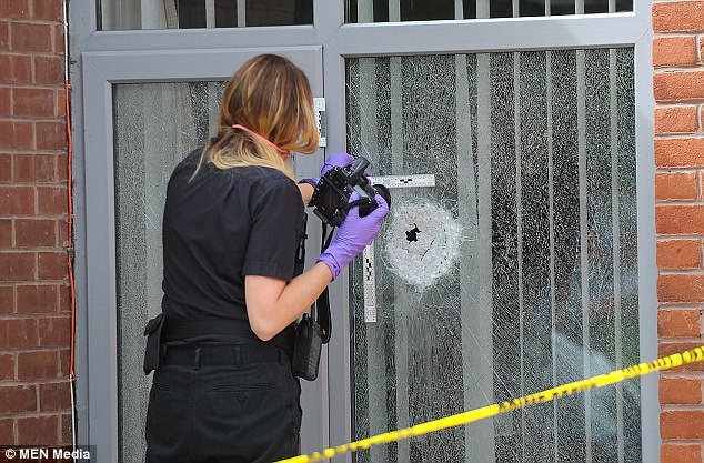 Two shots were fired through windows, which are seen here being inspected by a police officer