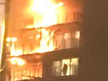 A firefighter is pictured on a balcony at the tower block and according to an eyewitness was seen leaping onto another burning balcony shortly after  