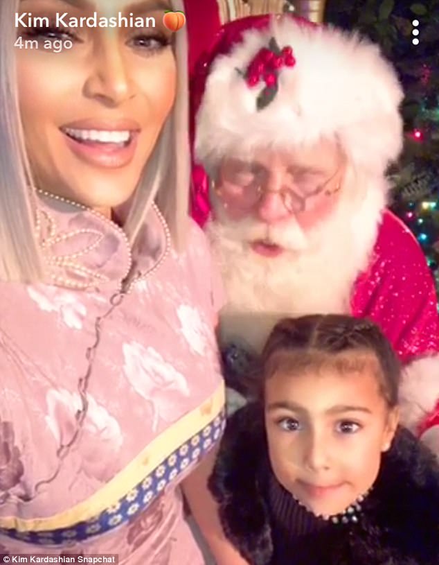 Cute smile: Four-year-old North smiled while sitting on Santa's lap