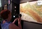 Kobieta fotografuje dużą mapę ścienna przedstawiającą Galicję z przełomu XIX i XX wieku 