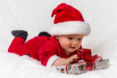 Santa baby girl lying on white blanket with gift stock photography