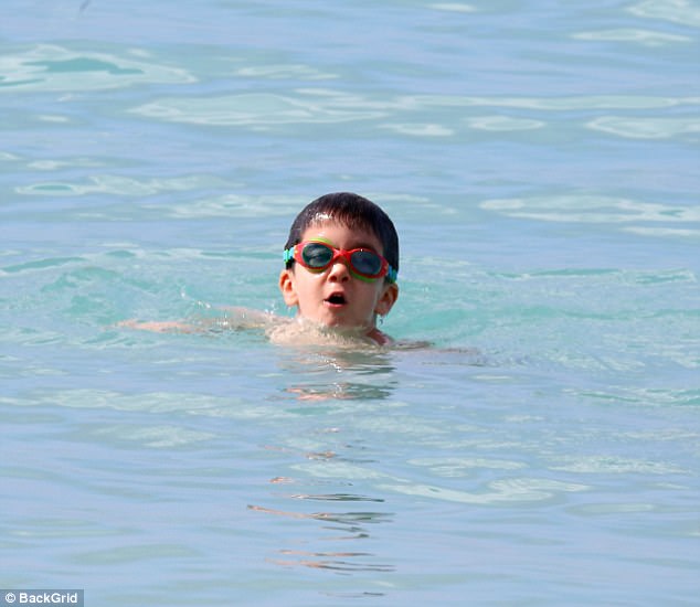 Having a ball: Meanwhile their son Eric, three, enjoyed a dip in the sea with his nanny