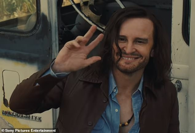 Friendly: The man slowly turns around to reveal himself as Charles Manson (Damon Herriman) before surprisingly flashing a big smile and waving toward him