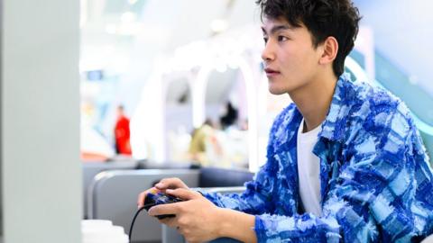 Asian man playing a video game