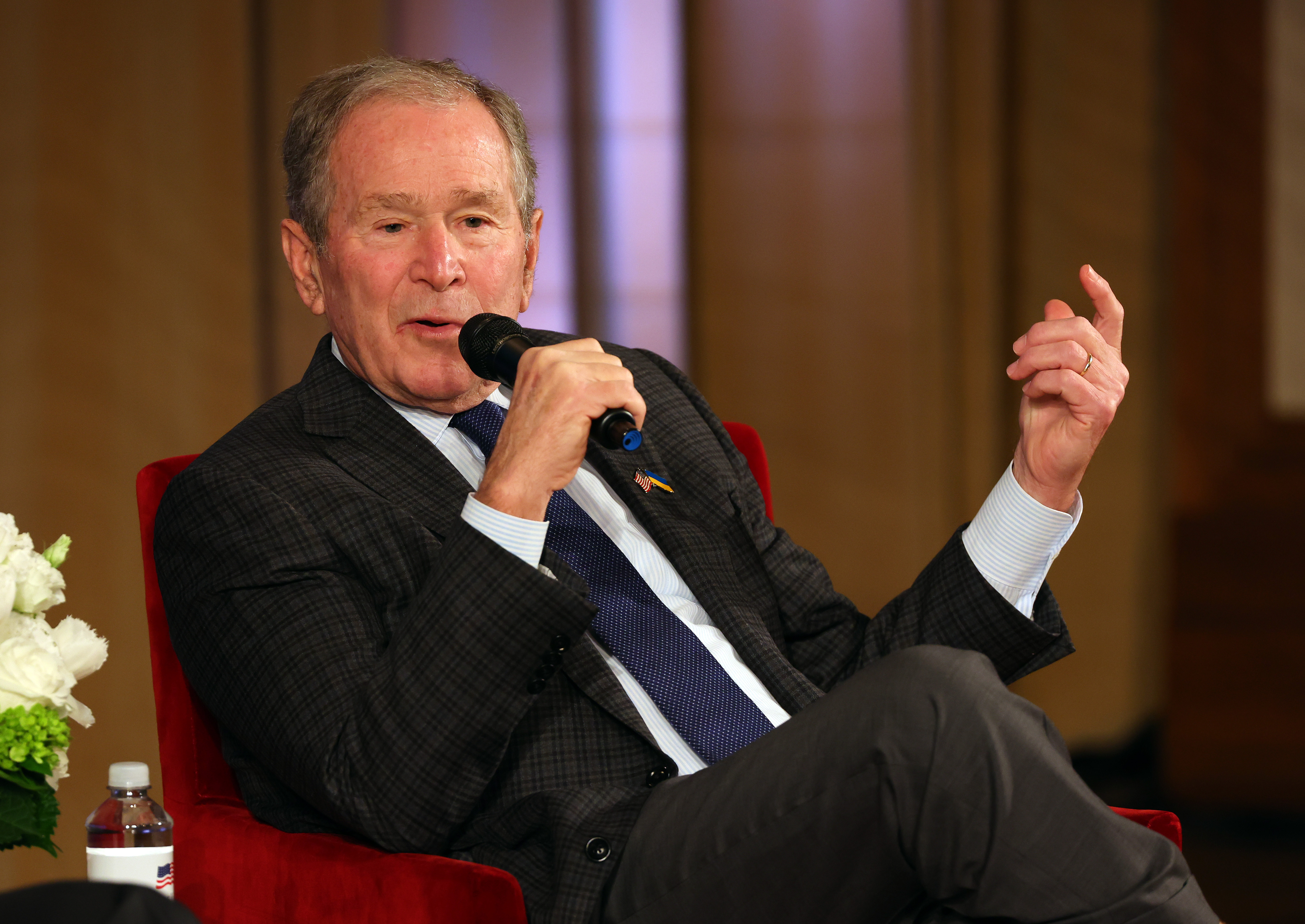 Bush sits in a chair and speaks into a microphone.