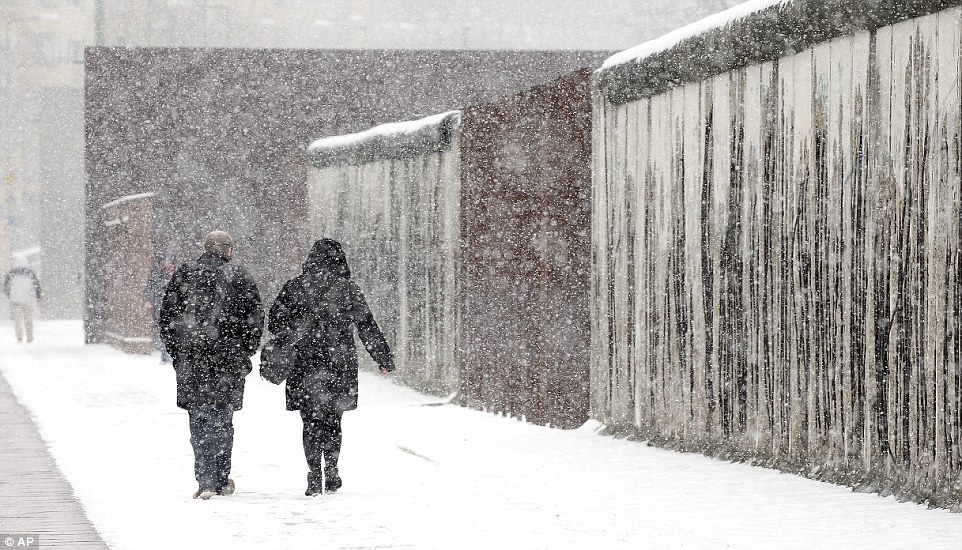 Berlin was particularly badly affected by the snow on Tuesday, with most of the city receiving a thick coating. Here a man and a woman walk alongside a section of the Berlin as the flakes fall