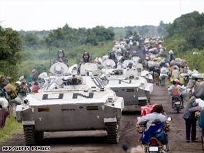 U.N. vehicles on Monday pass between lines of civilians fleeing fighting north of Goma, Congo.