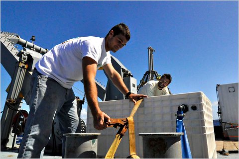 Nick Rollins and Willie Haskell secure an incubator to the deck of the research vessel Melville.