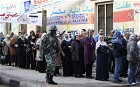 Egyptian soldier guards as Egyptians wait to cast their votes during parliamentary elections in Cairo