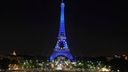 The Eiffel Tower illuminated in blue with gold stars, representing the EU flag