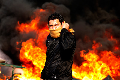 A protester stands in front of a burning barricade during a demonstration in Cairo January 28, 2011. Caption|REUTERS/Goran Tomasevic