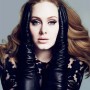 Adele mira de frente a la cámara, sosteniendo su rostro con sus manos; está portando guantes largos de cuero negro y una blusa de encaje negra.