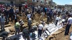 A handout picture released by the Syrian opposition's Shaam News Network shows people watching the mass burial on May 26
