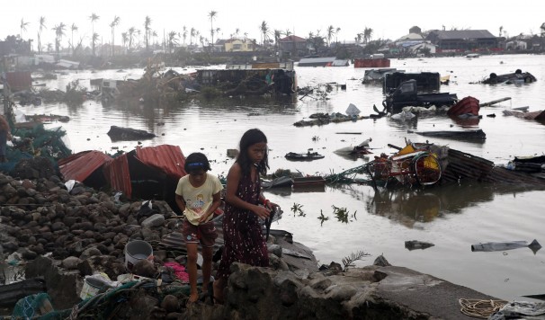 Residents walk near vehicles and debris floating on a river after Typhoon Haiyan devastated Tacloban, Philippines. 