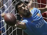 Barcelona forward Luis Suarez was pictured in goal saving an American football during training on Friday