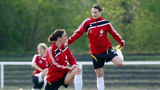 Birgit Prinz (L) and team mate stretch during a training session