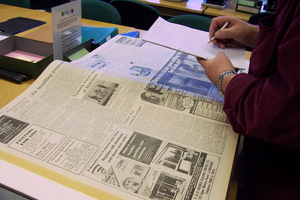 Photograph of a reader looking at an old newspaper