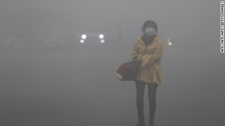A woman wearing a face mask walks in heavy smog in Harbin, northeast China&#39;s Heilongjiang province, on October 21, 2013. Choking clouds of pollution blanketed Harbin, a Chinese city famed for its annual ice festival on October 21, reports said, cutting visibility to 10 metres (33 feet) and underscoring the nation&#39;s environmental challenges.   CHINA OUT     AFP PHOTO        (Photo credit should read STR/AFP/Getty Images)
