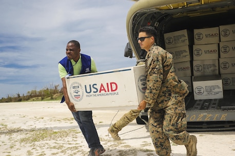 U.S. Marine Cpl. Steven Arroyo, a heavy equipment mechanic with Marine Wing Support Detachment 31, attached to Special Purpose Marine Air-Ground Task Force - Southern Command, aids an International Organization for Migration representative in carrying supplies at Jeremie, Haiti, Oct. 9, 2016. The Marines with SPMAGTF-SC and soldiers with Joint Task Force - Bravo are part of Joint Task Force Matthew, a U.S. Southern Command-directed team deployed to Port-au-Prince at the request of the Government of Haiti, on a mission to provide humanitarian and disaster relief assistance in the aftermath of Hurricane Matthew. (U.S. Marine Corps photo by Cpl. Samuel Guerra)