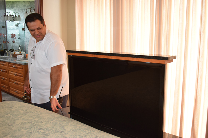 Mark Randall demonstrates a button-powered pop-up TV at the foot of a bed at The Palms.