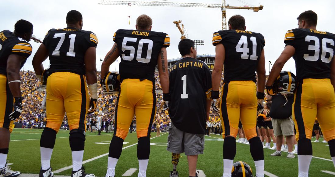 Football players stand with kid captain