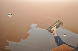 Applying finish coat to plasterboard ceiling