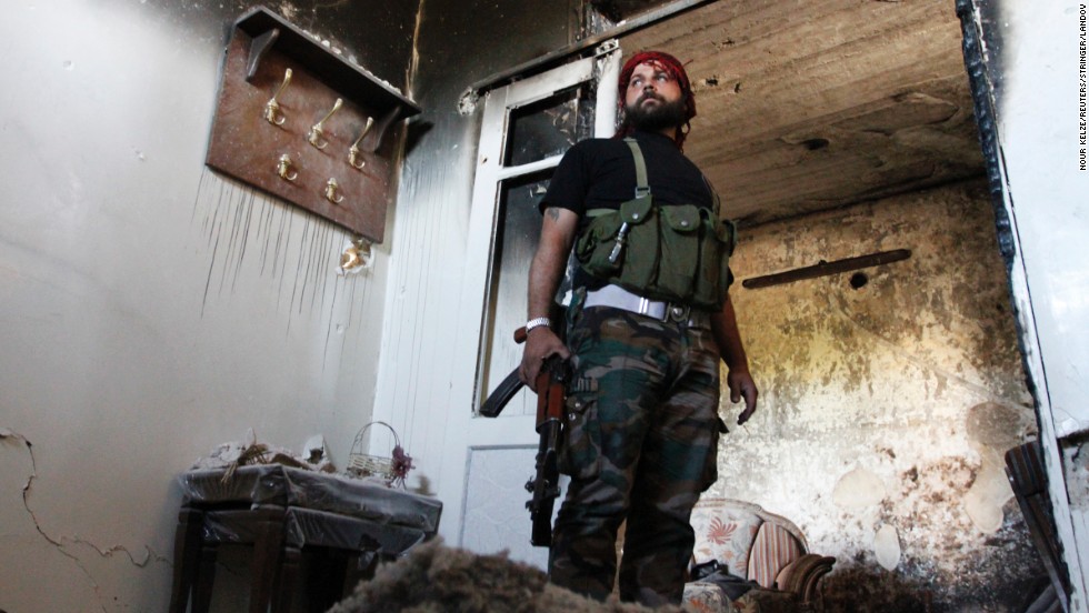A Free Syrian Army fighter stands guard inside a damaged house in Aleppo&#39;s Qastal al-Harami neighborhood on September 11. 