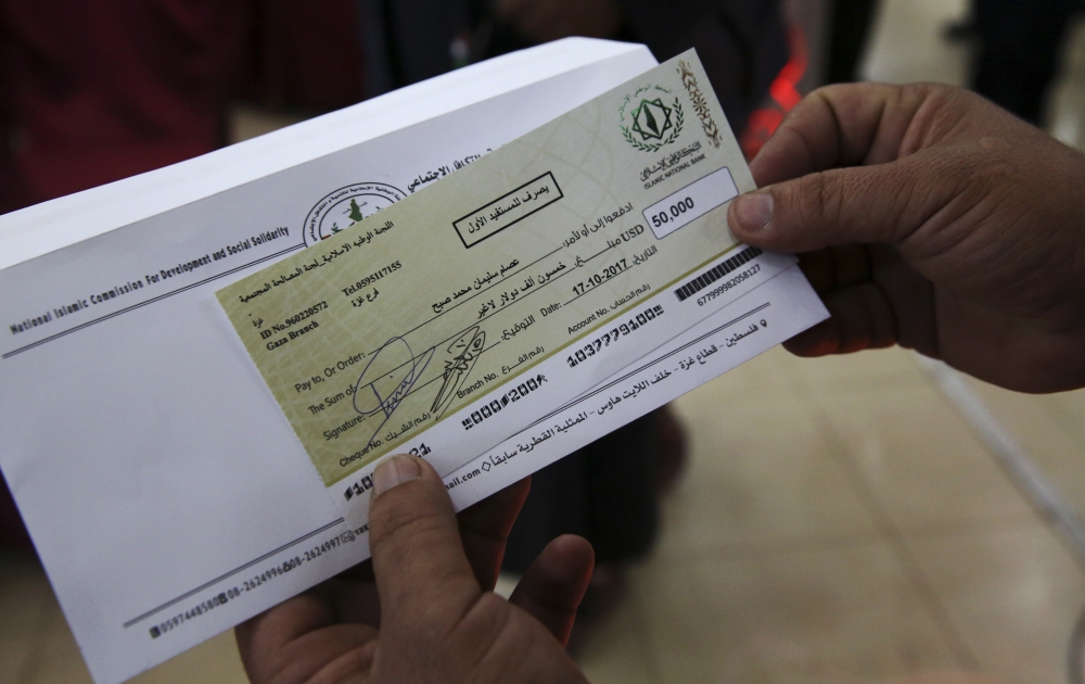 A relative shows a check for $50,000 to Esam Subeh's family during a social reconciliation ceremony in Beit Lahiya City, Gaza Strip. He was killed during Hamas and Fatah fighting in Gaza Strip in 2007. — AP