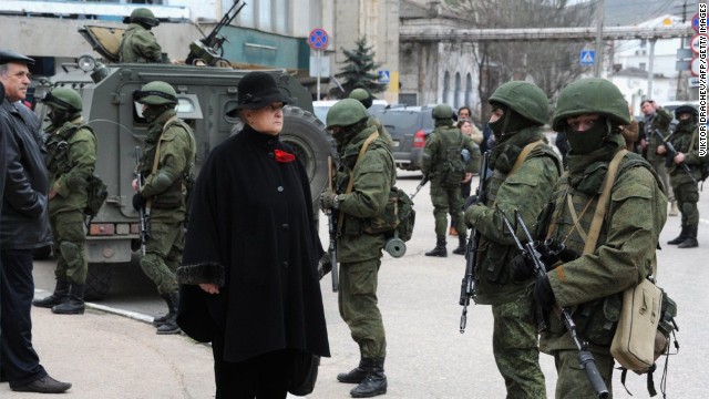A woman waits in front of unidentified men in military fatigues who were blocking a base of the Ukrainian frontier guard unit in Balaklava, Ukraine, on Saturday, March 1.