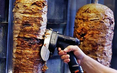 In this November 30, 2017, photo, a man slices cuts of meat from a rotisserie Doner spit inside a Doner restaurant cafe in Frankfurt, Germany.  (AP/Michael Probst, File)