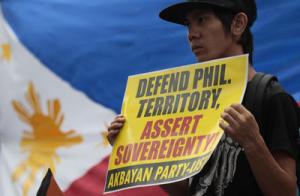 A Fililipino protester holds a slogan beside a Philippine flag during a rally outside the Chinese Consulate in suburban Makati, south of Manila, Philippines on Tuesday June 11, 2013. Source: East Asia Forum