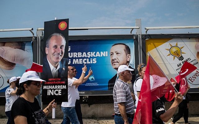 A supporter of Muharrem Ince, Presidential candidate of Turkey's main opposition Republican People's Party holds a banner reading "president of all of us" and people wave flags, as an election poster of the President of Turkey Recep Tayyip Erdogan is seen behind, on June 23, 2018 in Istanbul. ( AFP/ Yasin AKGUL)