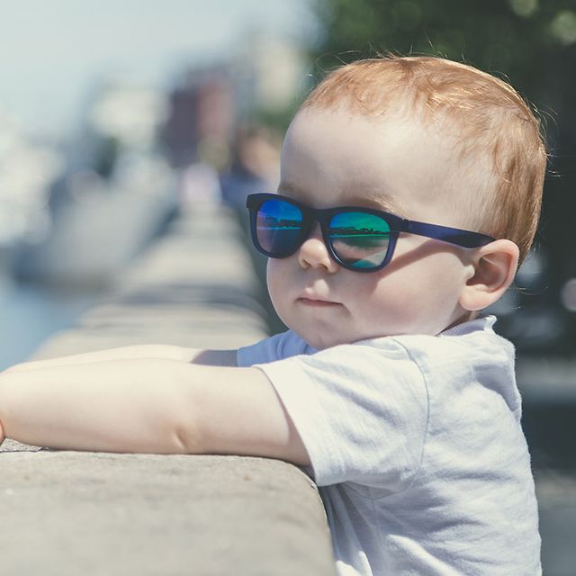 Child in sunglasses looking at river
