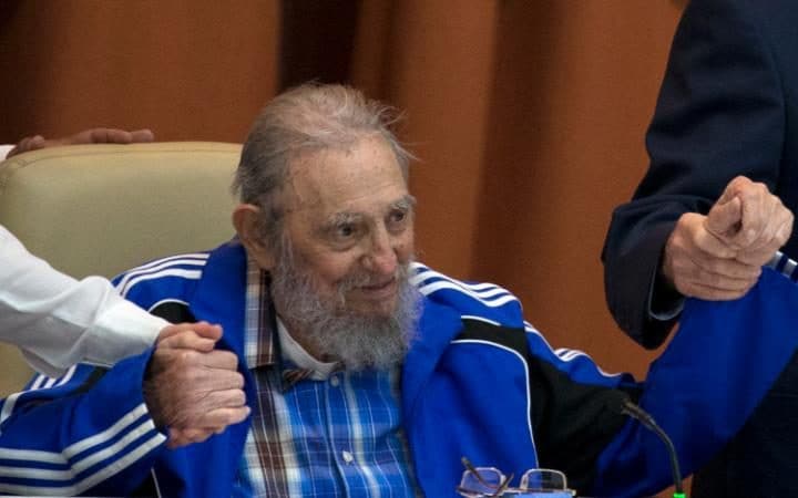 Fidel Castro sits as he clasps hands with his brother, Cuban President Raul Castro