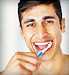 Closeup of a happy young guy brushing his teeth