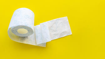 Roll of white toilet paper on a yellow background with empty space.
