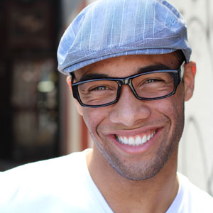 Young man with glasses and hat smiling