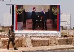 A soldier stands guard near a poster of Syria's President Bashar al Assad and his Russian counterpart Vladimir Putin in Rastan, Syria, June 6, 2018